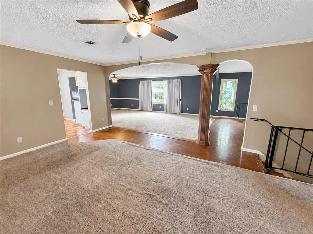 An open concept living area features diverse flooring and an ornate column.