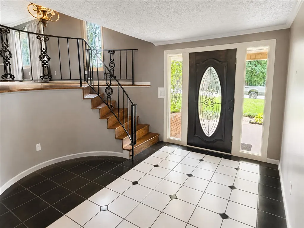 A graceful staircase with intricate ironwork ascends from a welcoming tiled entryway.