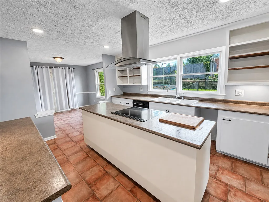 A well-lit kitchen with a central island and dual windows overlooking the private yard.