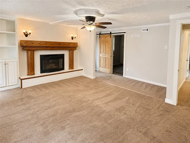 A comforting fireplace hearth with built-in cabinetry and a barn door entrance define this inviting living space.