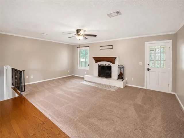 A well-lit living area features a charming fireplace with a brick hearth and a ceiling fan.