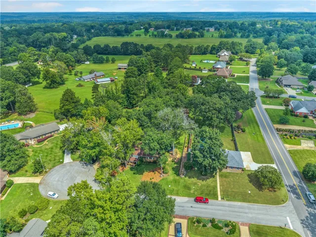 An aerial perspective reveals a serene community with residential homes nestled amidst lush green landscapes and mature trees.