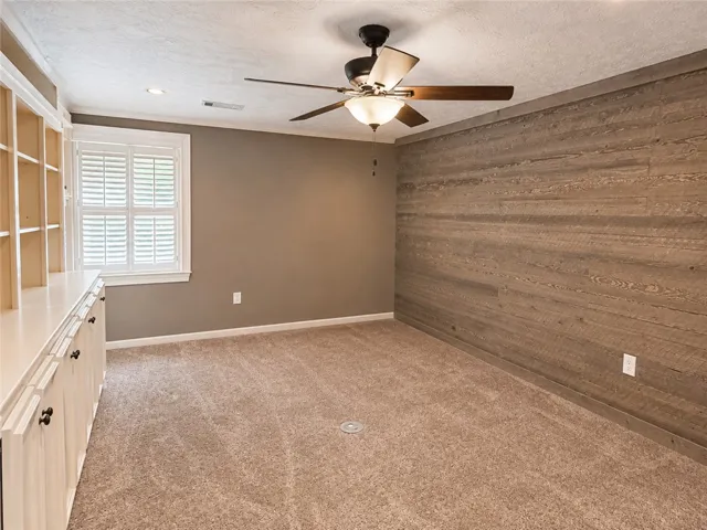 A versatile room features custom built-ins and a striking wood-paneled accent wall, perfect for work or relaxation.