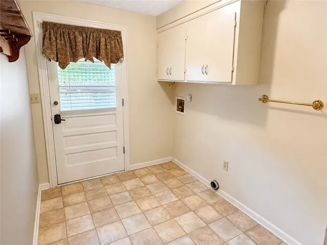 Practical laundry area features resilient flooring and convenient upper cabinetry.