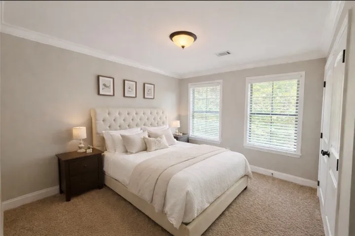 This inviting bedroom features natural light and crown molding, creating a serene and comfortable retreat.