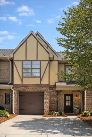 This townhome features charming Tudor-style elements, an attached garage, and a welcoming front entrance.