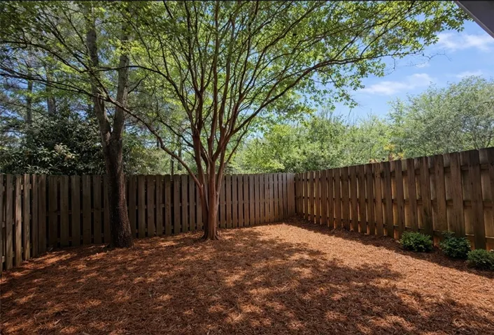 This private yard offers serene outdoor living with mature trees and natural ground cover.