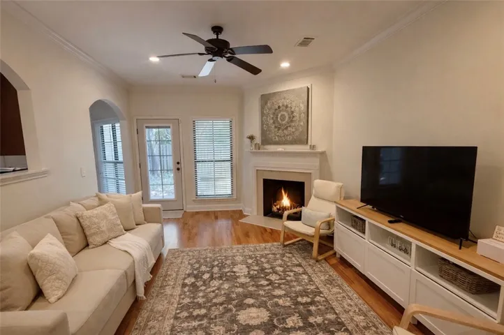 This inviting living room features a cozy fireplace, beautiful hardwood floors, and elegant crown molding.