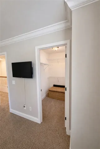 This cozy space features crown molding and plush carpeting, leading to a functional walk-in closet.