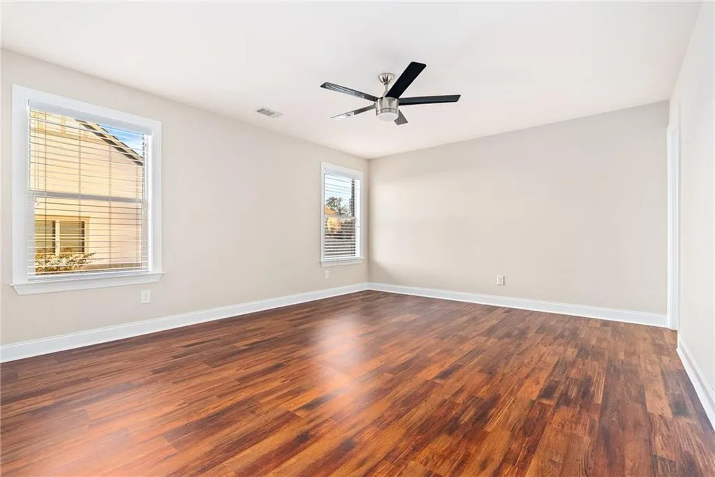 Well-lit living area boasts rich wood flooring and a modern ceiling fan.
