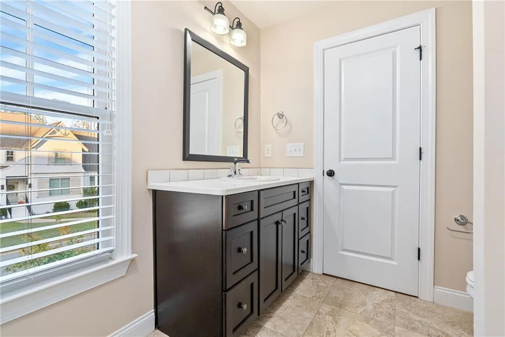 A well-appointed bathroom with a dark wood vanity, integrated sink, and mirror with overhead lighting.