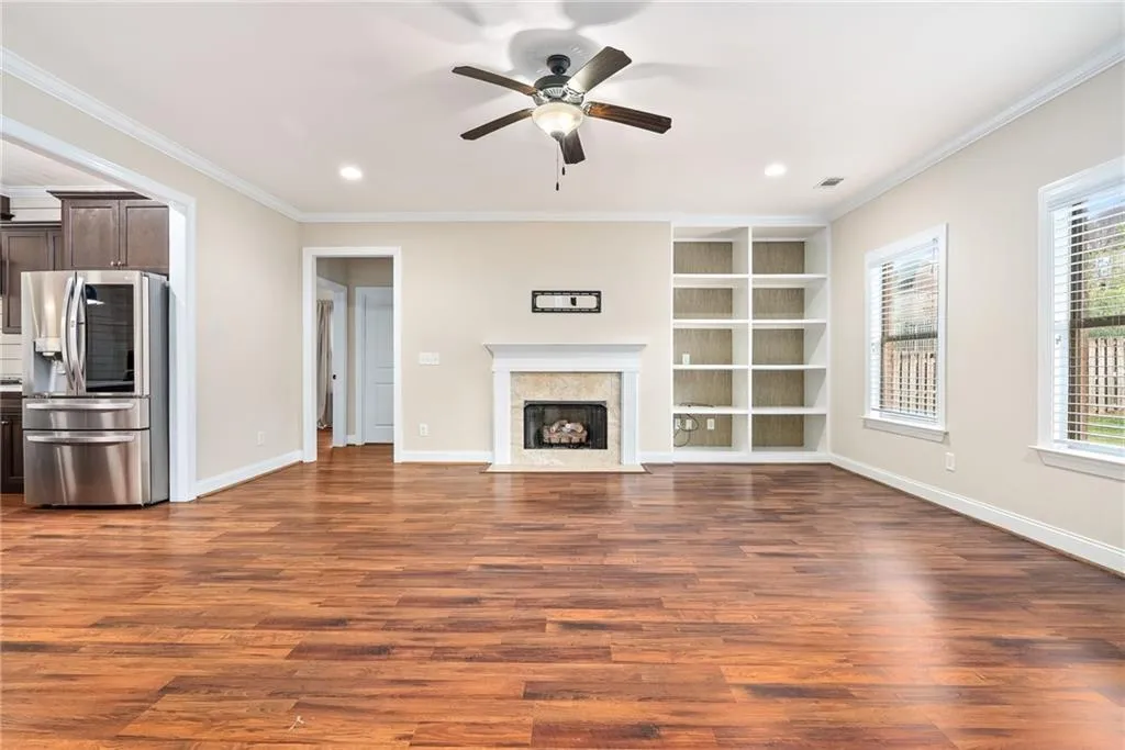 A spacious living area features rich hardwood flooring, built-in shelving, and a cozy fireplace, perfect for gatherings.