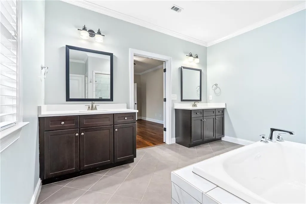 Dual vanities and a deep soaking tub create a personal spa experience in this well-appointed bath.