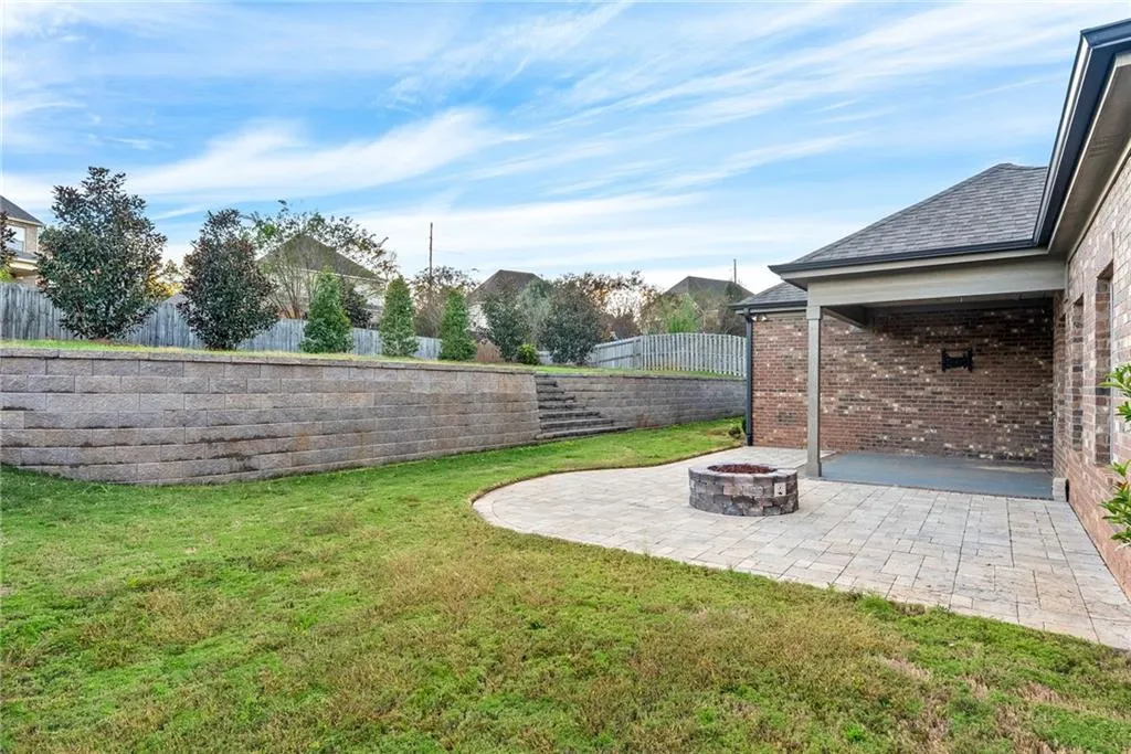 A well-manicured yard with a stone retaining wall and an inviting patio with a built-in fire pit.