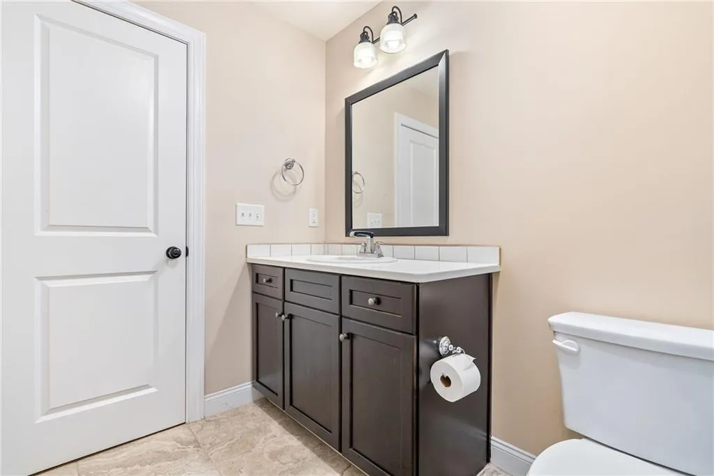 This bathroom features a contemporary dark wood vanity with a white countertop and a framed mirror.