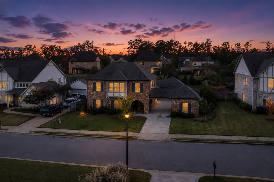 Witness the dramatic twilight colors unfold over this charming brick residence with welcoming illuminated windows.