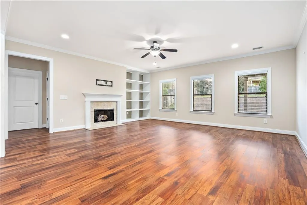 A living area features built-in shelving, rich wood flooring, and a cozy fireplace with a classic mantel.