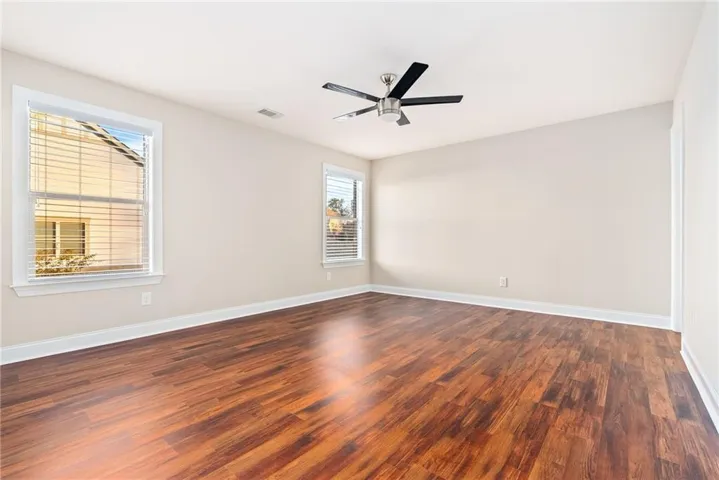 Well-lit living area boasts rich wood flooring and a modern ceiling fan.
