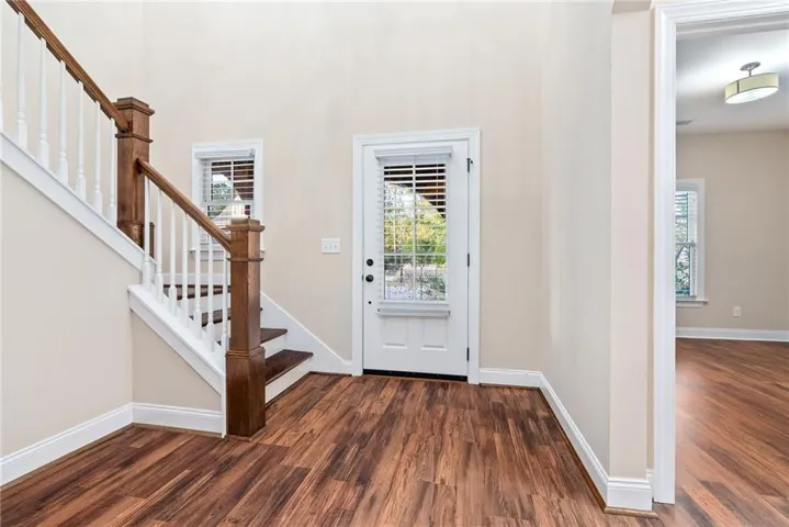 Enter into an inviting foyer with polished hardwood floors and a grand staircase.