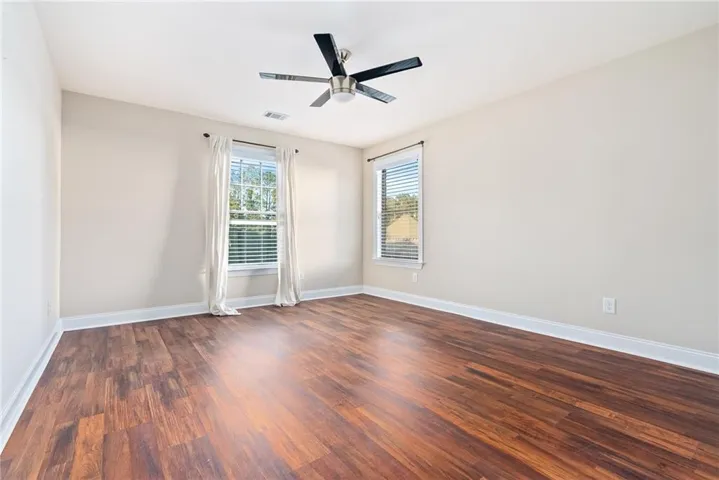 Rich wood flooring and generous windows create a welcoming bedroom space.
