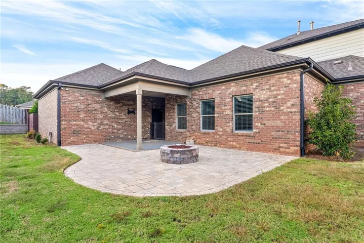 A private backyard oasis features a paved patio, covered porch, and a built-in stone fire pit.