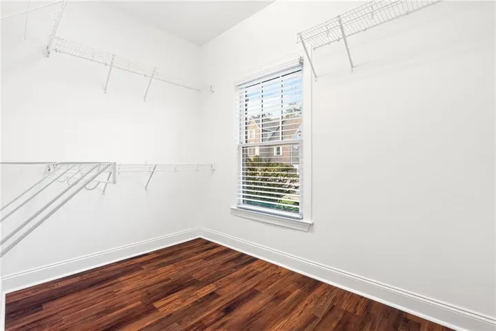 A well-lit closet with ample storage solutions and warm wood flooring.