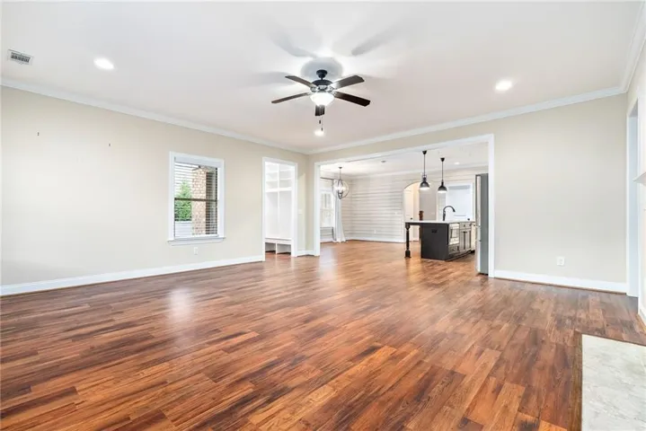 Rich hardwood flooring extends throughout this generous living area, opening into a contemporary kitchen.