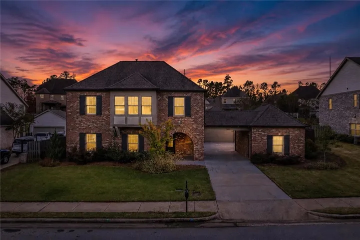 Dramatic sunset hues illuminate the brick facade of this welcoming residence with an attached garage.