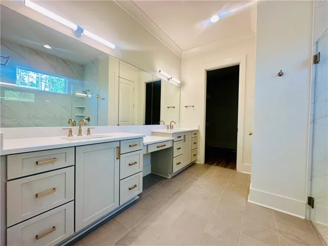 Dual vanities with quartz countertops and sleek brass hardware elevate this bathroom's sophisticated design.
