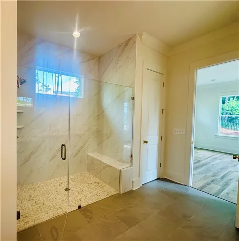 A spacious, naturally illuminated shower with elegant tile work and a built-in bench.