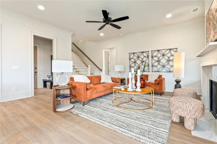 This bright living space features hardwood floors, a fireplace, and a striking staircase.