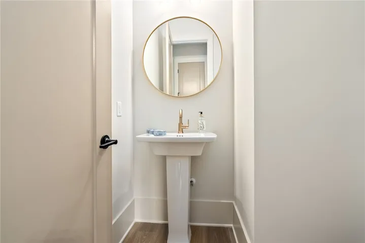 This powder room features a contemporary pedestal sink with a sleek gold-framed mirror.