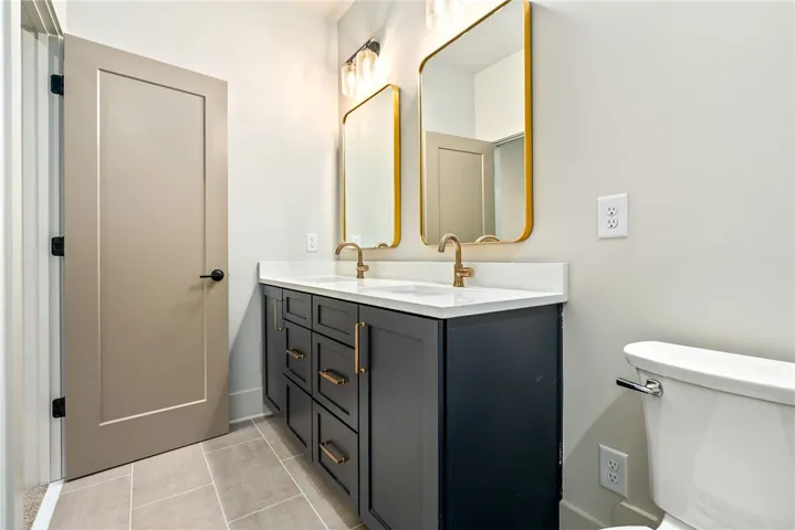 This bathroom boasts a sleek vanity with double sinks, complemented by elegant mirrors and lighting.
