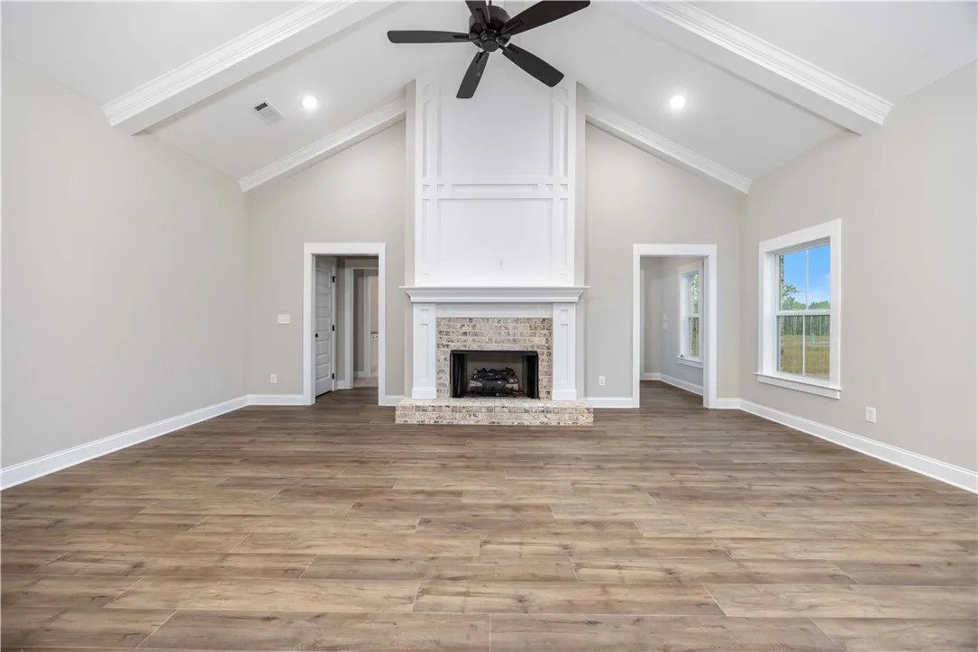 Vaulted great room with exposed beams and a stunning floor-to-ceiling fireplace with wainscoting detail.