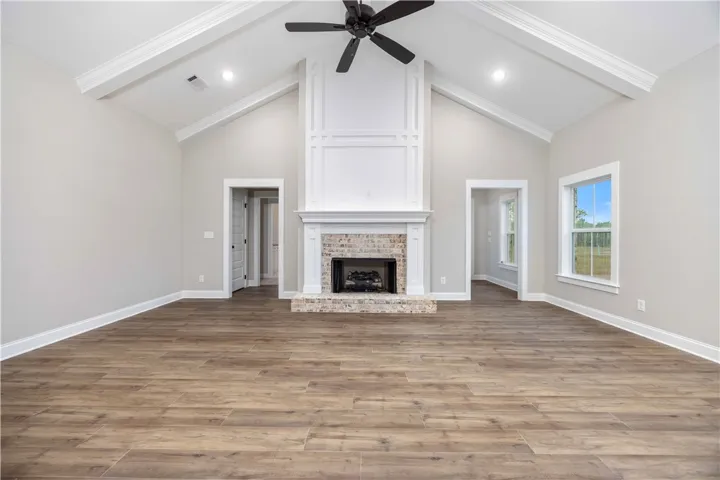 Vaulted great room with exposed beams and a stunning floor-to-ceiling fireplace with wainscoting detail.
