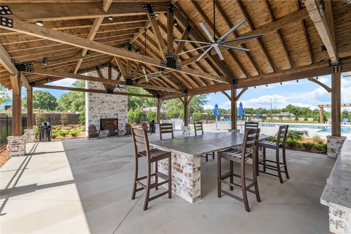 This spacious outdoor living area features an impressive wood-beamed ceiling and brick fireplace.