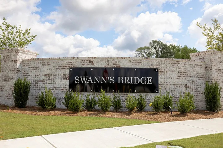 This grand entrance features a brick wall and manicured landscaping, welcoming residents and guests.