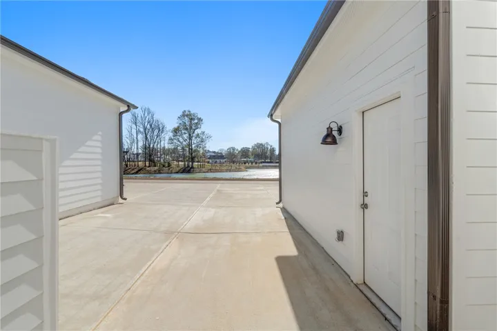This concrete path separates two structures, offering a view of the water and distant trees.