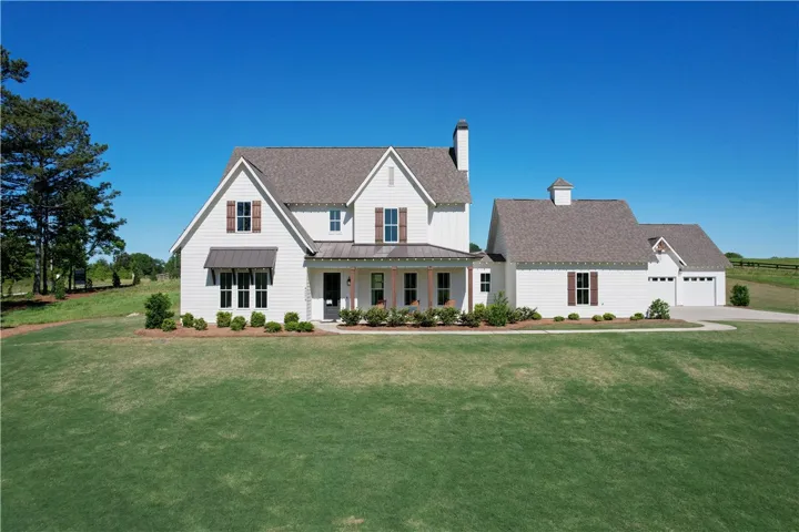 This charming farmhouse-style residence features a welcoming front porch and an attached garage.
