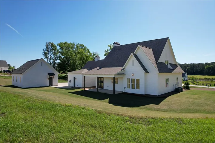 This newly built home features pristine siding, a covered patio, and lush landscaping.