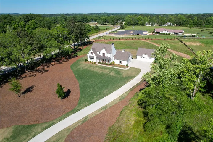 This expansive estate features a charming farmhouse-style residence with a detached garage, set amidst lush greenery.