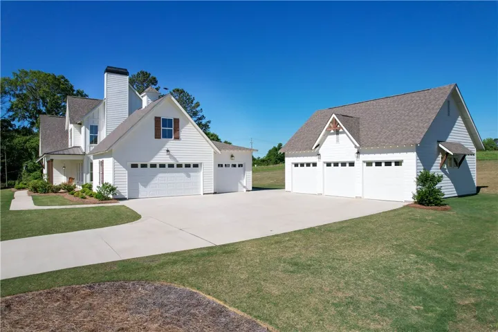 This captivating exterior showcases a spacious driveway and multiple garages under a clear blue sky.