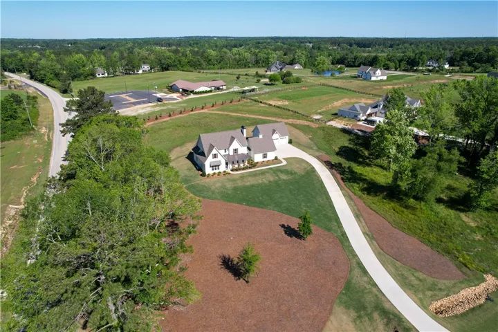 Perched atop a hill, this new construction home features a winding driveway and lush landscape.