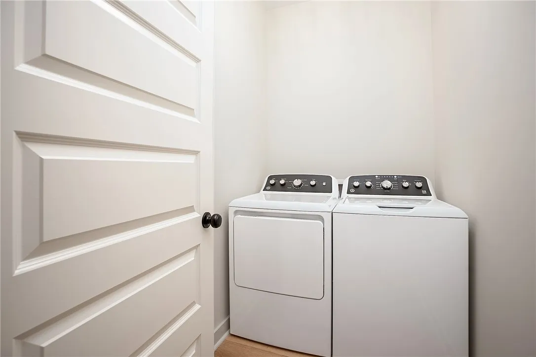 An organized laundry closet features dedicated hookups alongside wood flooring.