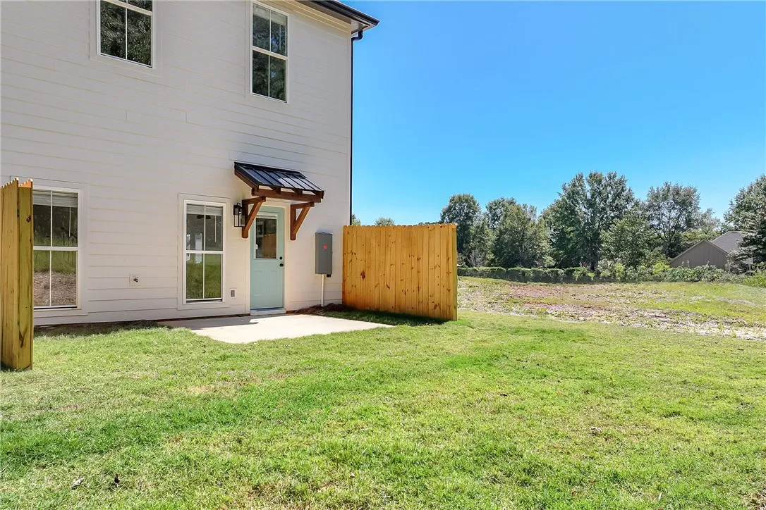 A concrete patio extends into the grassy lawn bordered by wooden privacy fencing.