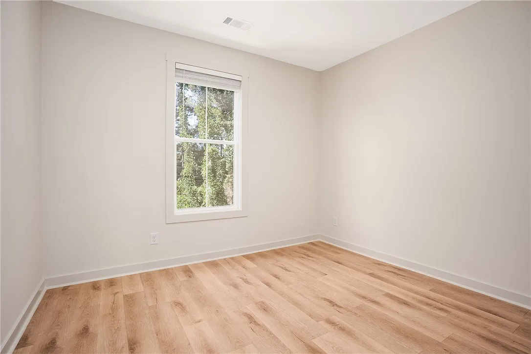 Rich wood-plank flooring warms a clean-lined interior filled with natural light from a single window.