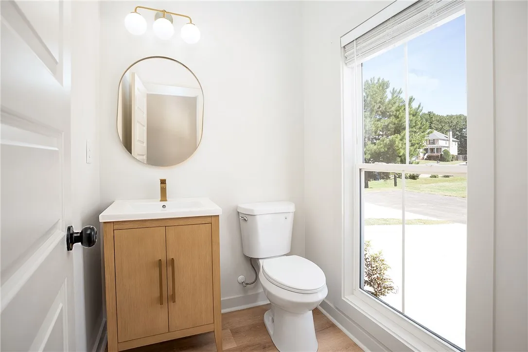Natural light streams through a large window into this modern powder room with wood flooring.