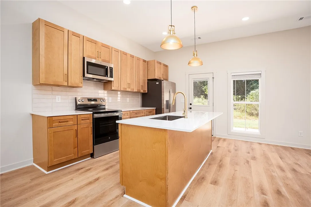 Warm wood cabinetry and an island anchor this modern kitchen featuring durable hard-surface flooring.