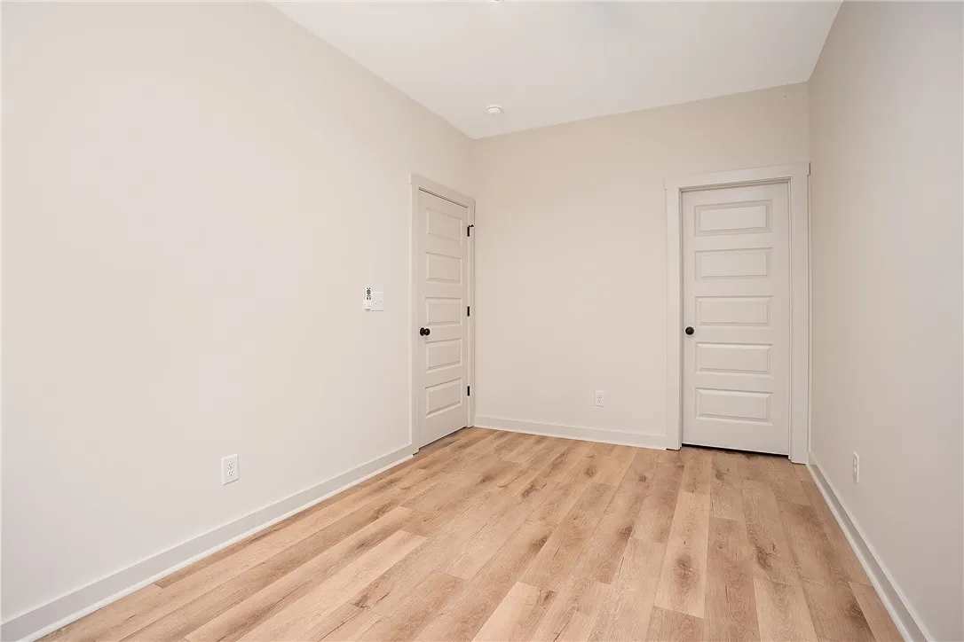 A minimalist room showcases crisp neutral walls paired with clean-lined wood flooring.