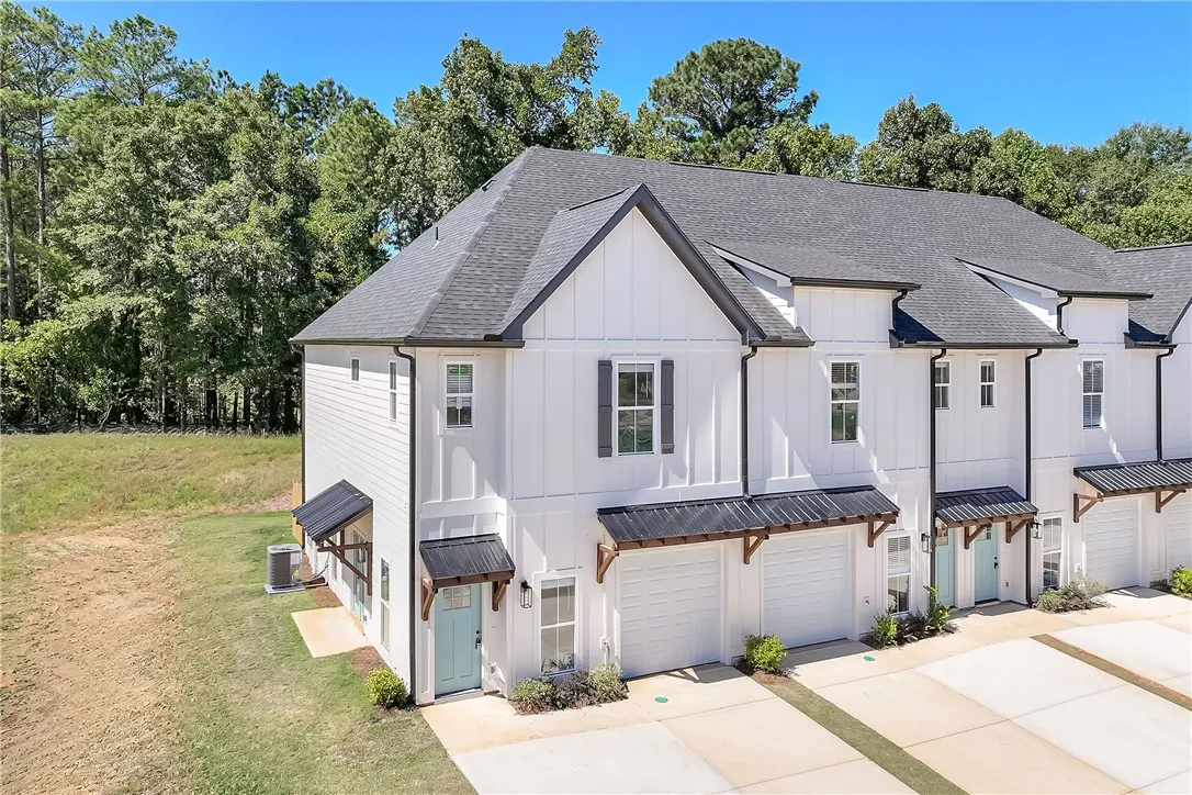 A modern multi-level exterior displays clean board and batten siding framed by a dense treeline.